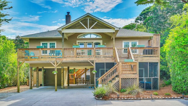 A two-story house with a covered front porch, a staircase, and a large window. - Steps to Beach! Emerald Isle Group Escape w/ Yard (Emerald Isle)