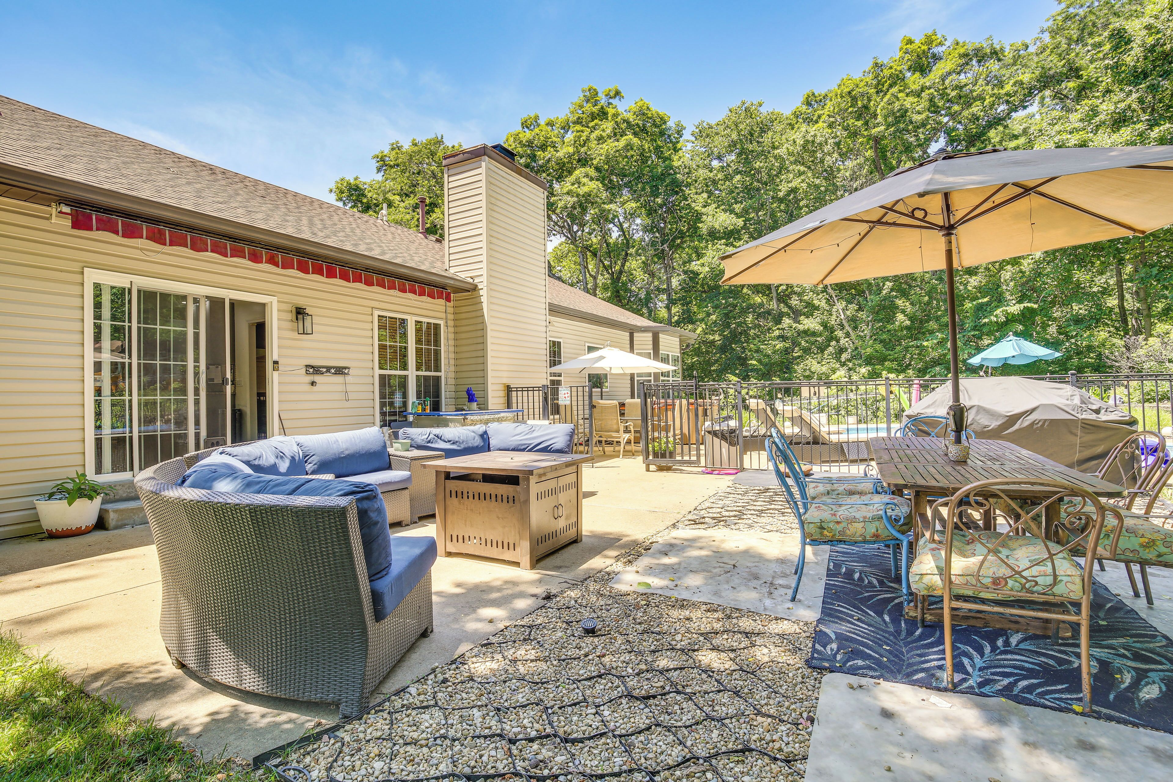 A patio with wicker furniture, a table with chairs, and umbrellas.