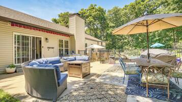 A patio with wicker furniture, a table with chairs, and umbrellas.