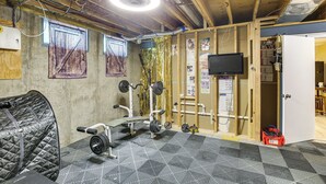 A gym with exercise equipment, a bench, and a wall-mounted TV.