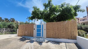 Una entrada protegida con una puerta azul, cerca de madera y un árbol en lo alto.