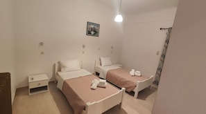 Ein Zimmer mit zwei Betten, einem Nachttisch, einem Wandbild und einer Pendelleuchte.