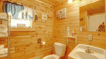A wooden cabin bathroom with a toilet, sink, and towel rack.