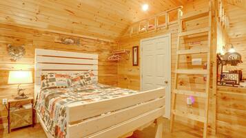 A wooden cabin bedroom with a bed, a nightstand, a wardrobe, and a 'No Smoking' sign.