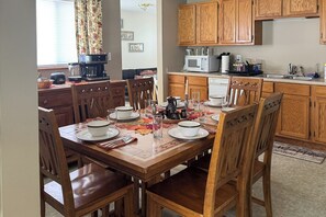 A dining area with a wooden table set for four, surrounded by wooden chairs.