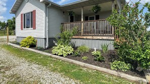 A single-story house with a porch, a small garden, and a clear blue sky. - Families Welcome! Corinth Escape w/ Lake Views (Corinth)