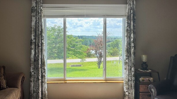 A room with a large window, a sofa, a chair, and a small table with a lamp. - Families Welcome! Corinth Escape w/ Lake Views (Corinth)