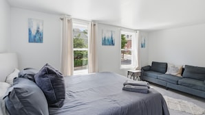 Ein Schlafzimmer mit einem Bett, einem Schlafsofa und zwei Fenstern mit Vorhängen.