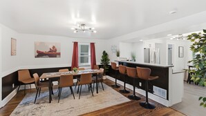 Ein moderner Essbereich mit Holztisch, braunen Stühlen, einer Bar und einer großen Kübelpflanze.