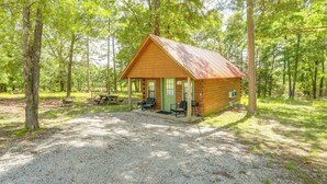 Eine rustikale Holzhütte mit Veranda, Picknicktisch und zwei Stühlen.