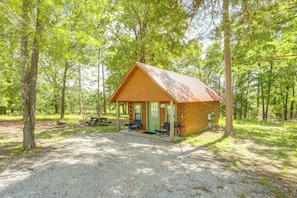 A rustic cabin with a porch, a picnic table, and two chairs. - Close to Blanchard Caverns! Nature-centric Cabin (Fifty-Six)
