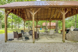 A covered outdoor seating area with tables and chairs, a grill, and a stone feature. - Close to Blanchard Caverns! Nature-centric Cabin (Fifty-Six)