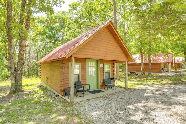 Eine Holzhütte mit Veranda, zwei Stühlen und einem Schotterweg.