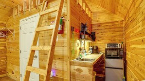 A wooden cabin interior with a kitchen area, including a sink, stove, and refrigerator.