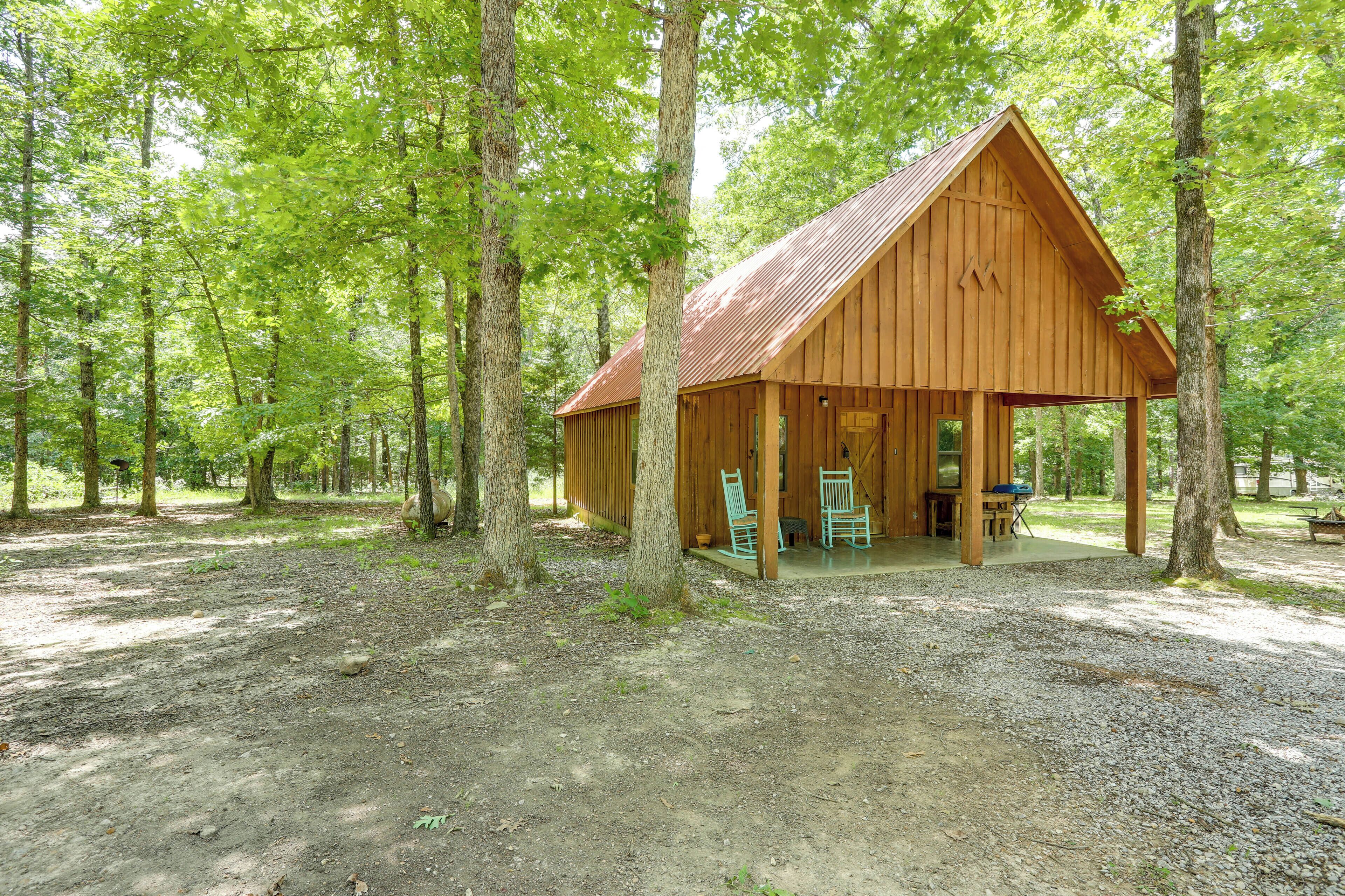 Une cabane en bois avec un porche, entourée d’arbres.