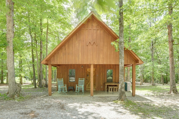 Une cabane en bois avec une véranda, deux fauteuils à bascule et une table.