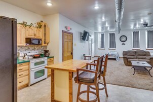 Cocina con armarios de madera, microondas y estufa. Se aprecia una mesa de comedor con sillas.