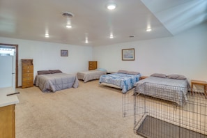A bedroom with three beds, a wooden dresser, a desk, and a ceiling fan.