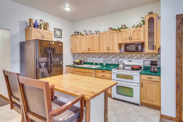 A kitchen with wooden cabinets, a stainless steel refrigerator, a microwave, and a stove.