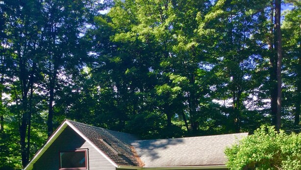 A house with a sloped roof, a front porch with two chairs, and a well-maintained lawn.