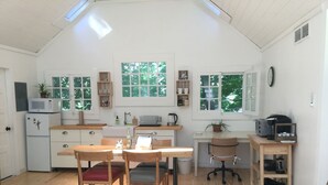 A compact kitchen with wooden cabinets, a microwave, a sink, and a dining area with chairs and a table.