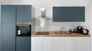 A modern kitchen with a built-in oven, stainless steel range hood, and a sink with a faucet.