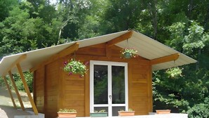 A wooden cabin with a sloped roof, a front door, and potted plants on the porch. - Le Chalet de Pierre Sèche – up to 8 guests (Chaumard)