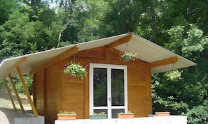 Eine Holzhütte mit geneigtem Dach, einer Haustür und Blumentöpfen auf der Veranda.