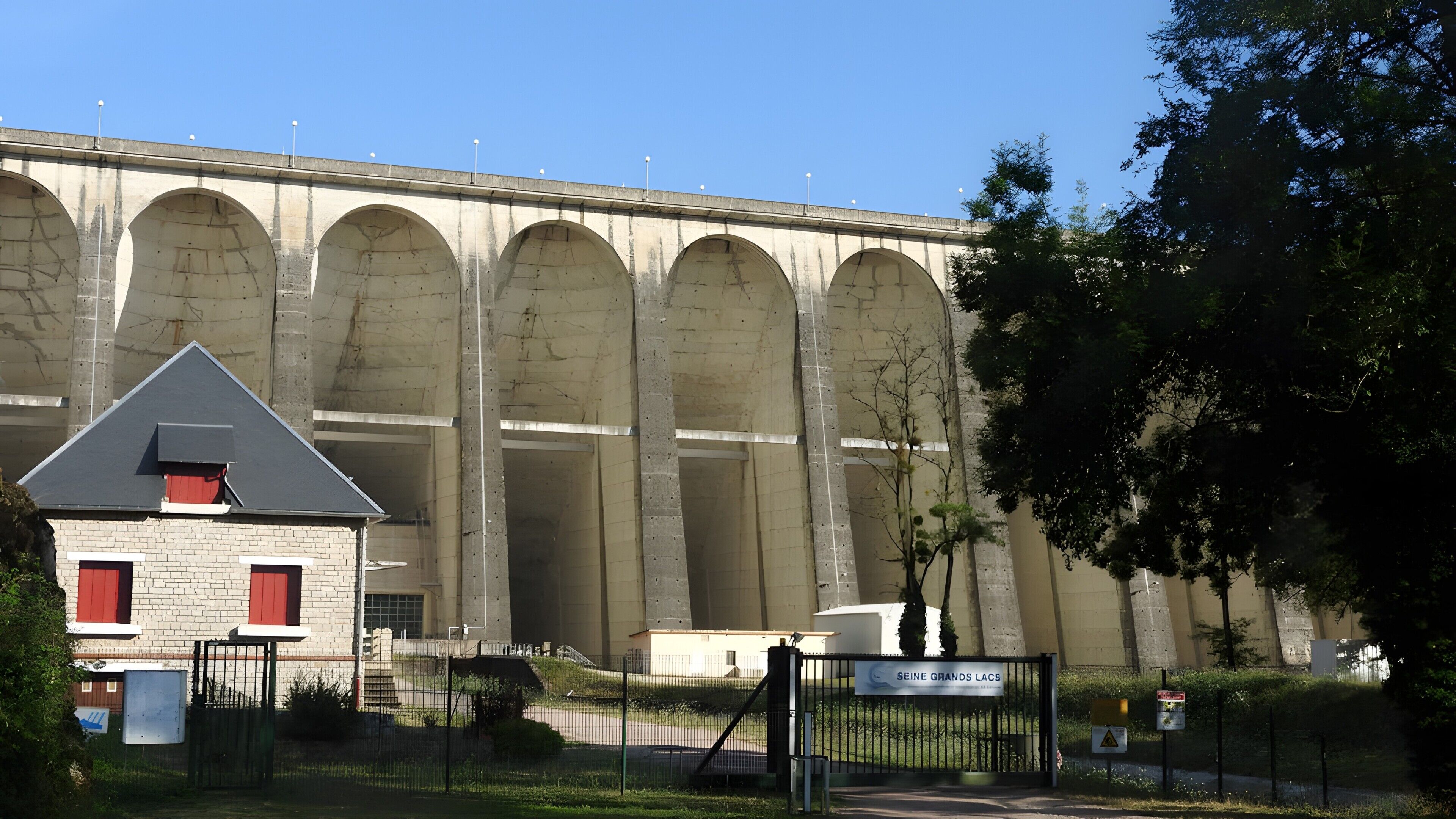 Un edificio grande con varios arcos, una entrada con portones y un letrero que dice 'SEINE GRANDS LACS'.