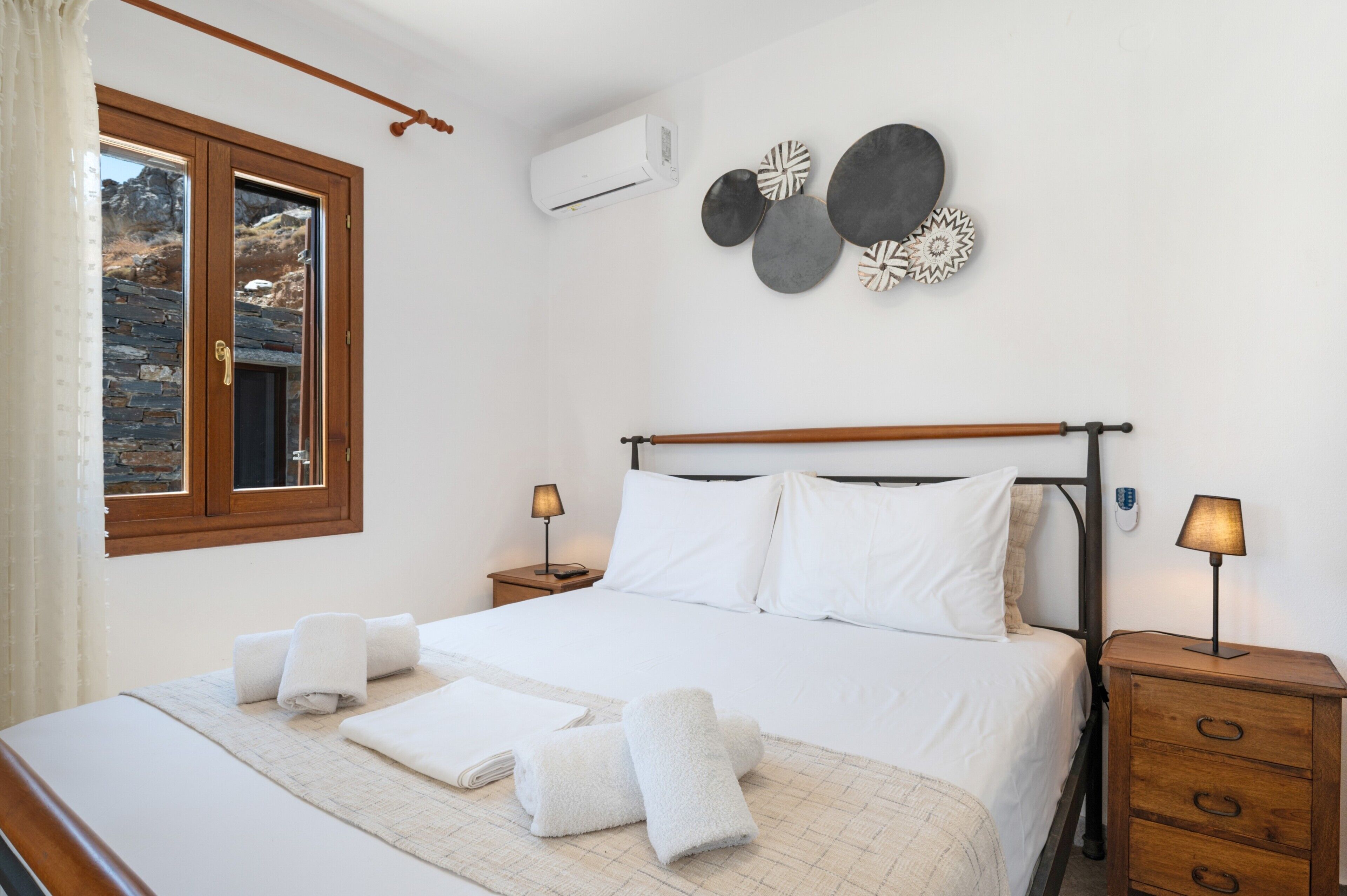Ein Hotelzimmer mit einem Bett, zwei Nachttischen, einem Fenster und Wandgestaltungen.