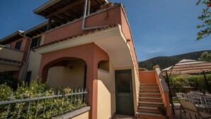 A two-story building with a balcony, a staircase, and outdoor seating. - Atzori Home - Sant'Anna Arresi (Sant`Anna Arresi)