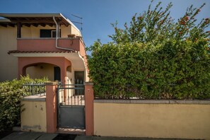 A two-story building with a balcony, a gated entrance, and a dense hedge. - Atzori Home - Sant'Anna Arresi (Sant`Anna Arresi)