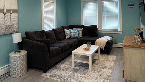 A living room with a dark-colored sofa, a white coffee table, and a ceiling fan. - Renovated Beach Condo, 1 Block to the Beach (Wildwood)