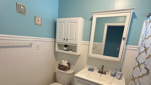 A bathroom with a toilet, sink, cabinet, mirror, and decorative items. - Renovated Beach Condo, 1 Block to the Beach (Wildwood)