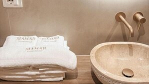Un baño con un lavabo redondo, una pila de toallas y un espejo.