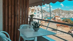 Un balcón con mesa y sillas, vista a un pueblo, y un muro de madera.