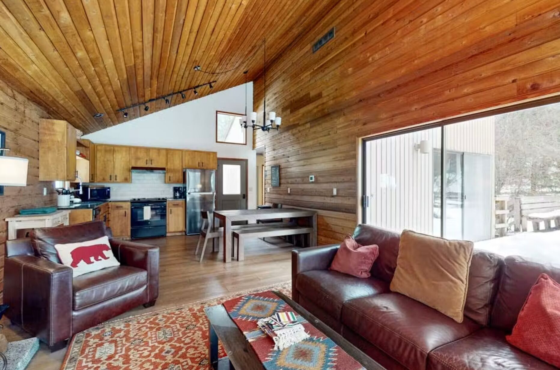 Un vaste espace de vie comprenant un canapé en cuir, une table basse et un plafond en bois.