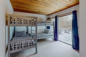 A room with bunk beds, a window with curtains, and a view of the outside. - Meadow's Edge at Black Butte Ranch—2 pets allowed (Sisters)