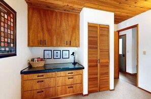 A wooden cabinet with drawers, a framed picture collection, and a basket on a counter. - Meadow's Edge at Black Butte Ranch—2 pets allowed (Sisters)