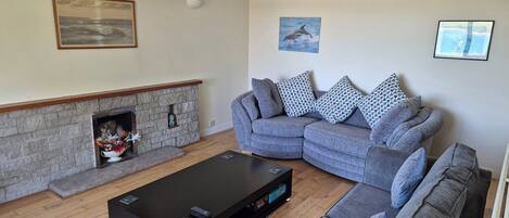 A living room with a sectional sofa, a fireplace, a black coffee table, and a ceiling with recessed lighting.
