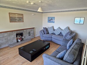 A living room with a sectional sofa, a fireplace, a black coffee table, and a ceiling with recessed lighting. - Bryn Y Felin (Y Felinheli)
