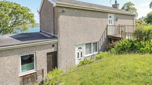 Et toetagers hus med facade i sten, en balkon og udsigt over vandet.