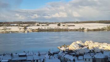 A residential area with snow-covered rooftops and a river in the background.