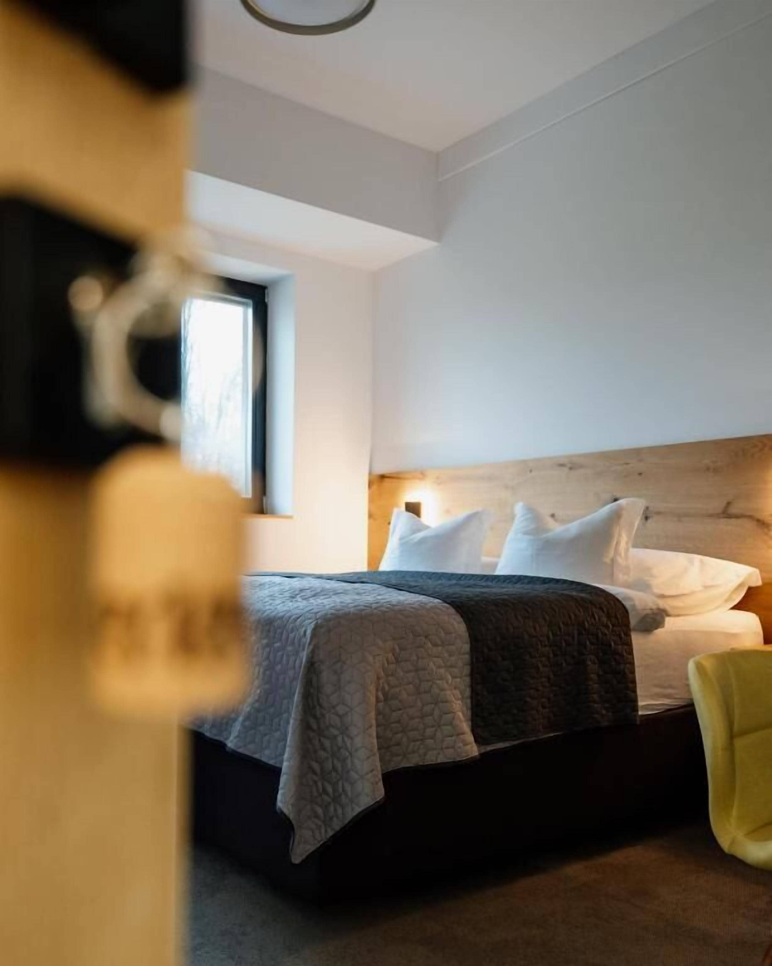 Quarto com cama, almofadas, mesa de cabeceira e janela.