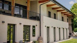 A building with a balcony, outdoor seating, and a paved walkway.