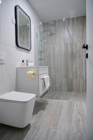 Deluxe tweepersoonskamer | Badkamer | Een douche, een haardroger, handdoeken, zeep