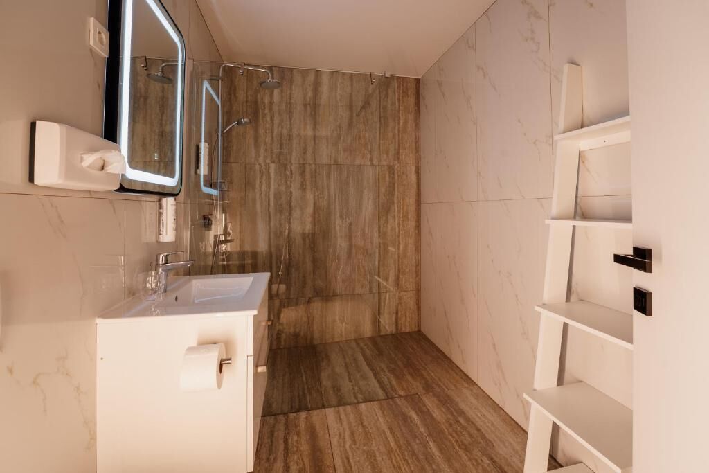 Un baño moderno con lavamanos, espejo y ducha.