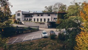 A modern building with a parking lot, surrounded by trees and greenery.