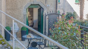A courtyard with a table and chairs, a door with a number, and a staircase.
