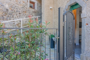 Ein Steinhaus mit einem Metallgitter, einer Treppe und einem kleinen Garten mit Pflanzen.